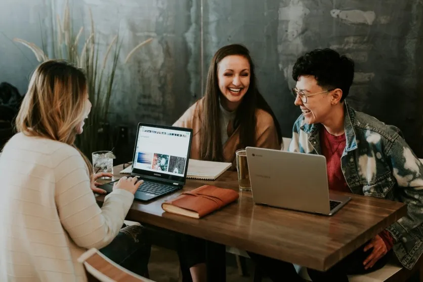 three people sitting front table laughing together